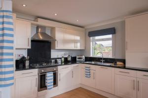 a kitchen with white cabinets and a sink and a window at Swallow Lodge with Hot Tub, dogs welcome sleeps 8, Great resort Facilities in Padstow