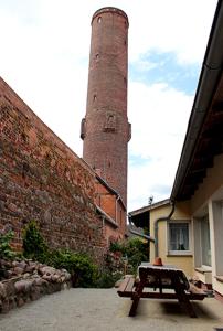 una torre de ladrillo con una mesa de picnic frente a un edificio en Pension am Schrotturm Tangermünde en Tangermünde