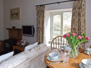 The Generals Cottage في Mitchel Troy: غرفة معيشة مع أريكة وطاولة مع زهور