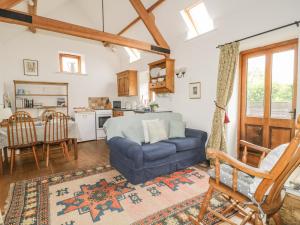 a living room with a blue couch and a kitchen at High Park Barn in Uffculme