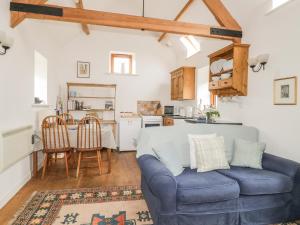 a living room with a blue couch and a kitchen at High Park Barn in Uffculme