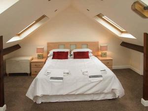 um quarto com uma grande cama branca com almofadas vermelhas em 302 Over Lane Cottage em Belper