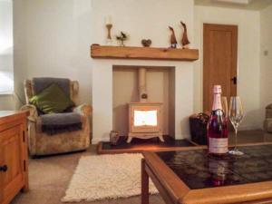 a living room with a fireplace and a bottle of wine at Tyddyn Gyrfa Cottage in Cemaes Bay