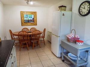 eine Küche mit einem Tisch und einem weißen Kühlschrank in der Unterkunft Tyddyn Gyrfa Cottage in Cemaes Bay