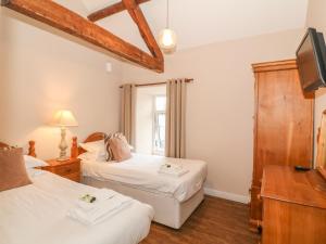 two beds in a room with a tv and a window at Hen Blas in Aberdaron