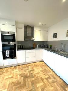 a kitchen with white cabinets and a wooden floor at Prosper House Apartment 5 in Norwich