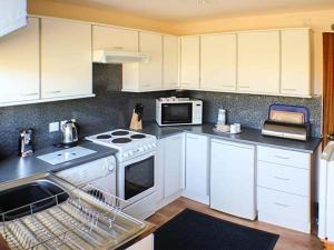 a kitchen with white cabinets and a sink and a dishwasher at Ardmore in Trumpan