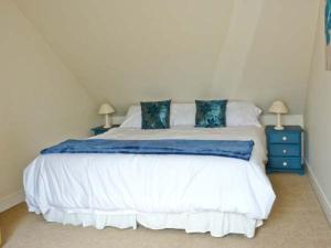 a bedroom with a large white bed with blue pillows at Kennels Cottage in Saint Boswells