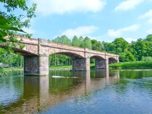 eine Steinbrücke über einen Fluss in einem Park in der Unterkunft Kennels Cottage in Saint Boswells