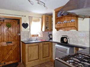 a kitchen with wooden cabinets and a stove top oven at 3 Apsley Cottages in Chartham