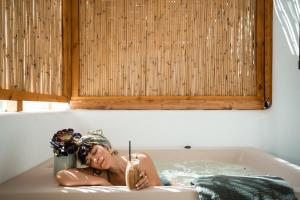 a woman laying in a bath tub at Koukoumi Vegan Boutique Hotel in Ano Mera