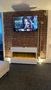 a living room with a tv on a brick wall at BvApartments Dealhouse Nine in Huddersfield