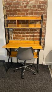 a desk with a chair in front of a brick wall at BvApartments Dealhouse Nine in Huddersfield