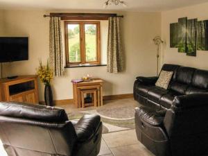 a living room with two leather couches and a television at Tyn Y Celyn Canol in Clocaenog