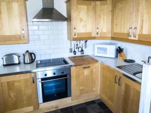 a kitchen with wooden cabinets and a stove top oven at The Summer Palace in Middleham