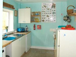 a blue kitchen with a sink and a refrigerator at Y Garth in Ferryside