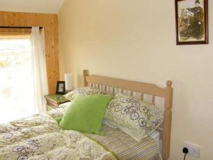 a bedroom with a bed with green pillows and a window at Y Garth in Ferryside