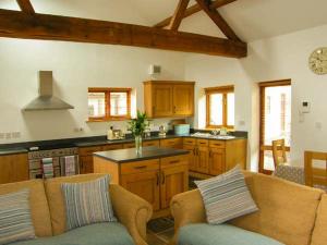 a kitchen with wooden cabinets and a couch in a room at Riverside Barn in Gilwern