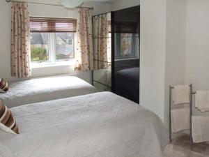 a bedroom with two beds and two windows at Hour Cottage in Stow on the Wold