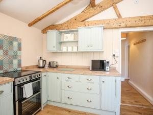 a kitchen with white cabinets and a stove top oven at Bryn Coed in Porthmadog