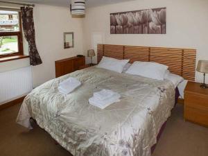 a bedroom with a large bed with towels on it at Parsley Cottage in Conder Green