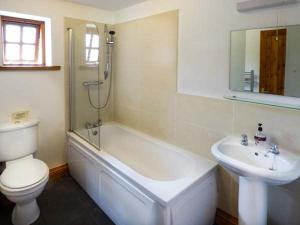 a bathroom with a toilet and a tub and a sink at Parsley Cottage in Conder Green