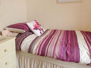 a bed with a purple and white comforter and pillows at Elizabeth House in Hornsea