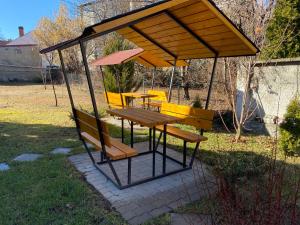 a gazebo with a picnic table and benches at Oreo Apartman in Eger