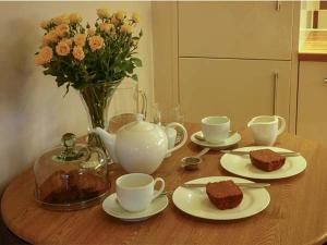 una mesa de madera con platos y tazas y un jarrón con flores en Bridleway Cottage, en Wennington