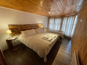 a bedroom with two beds and a wooden ceiling at HOTEL VOLKANICO in Curacautín