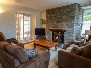 a living room with couches and a stone fireplace at Teifi House in Cilgerran