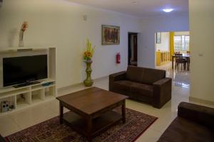 ein Wohnzimmer mit einem TV, einem Sofa und einem Tisch in der Unterkunft RESIDENCE IVOIRE in Accra