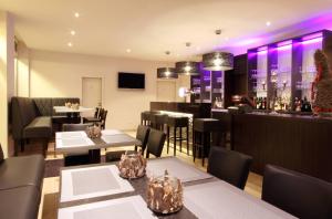 a restaurant with tables and a bar with purple lights at Hotel Borchers in Dörpen