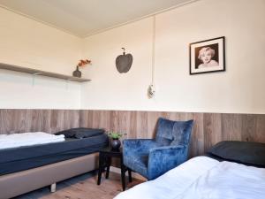 1 dormitorio con 2 camas y silla azul en Vakantiehuis de Strandloper Serooskerke Se08, en Serooskerke