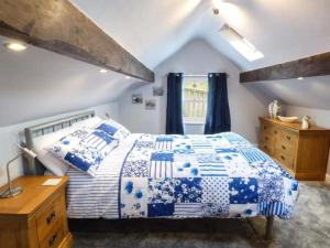 a bedroom with a blue and white bed and a window at Little Owl Barn in Warslow