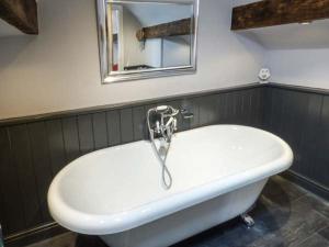 uma banheira branca na casa de banho com um espelho em Little Owl Barn em Warslow