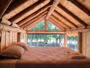 uma cama grande num quarto de madeira com uma grande janela em Chalé Refúgio Panorâmico em Canela