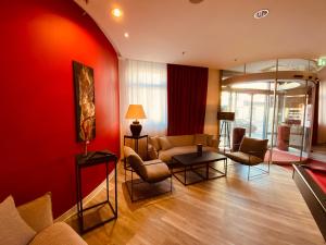 a living room with red walls and a couch and chairs at DORMERO Hotel Dresden City in Dresden