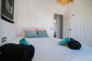um quarto com uma grande cama branca com almofadas azuis em Tarifa Watersports Residence em Tarifa