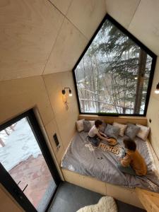 2 enfants assis sur un lit dans une petite maison dans l'établissement Domek na drzewie Ceprowo, à Szczyrk