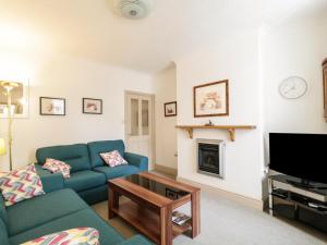 a living room with a blue couch and a fireplace at 1 Rubby Banks Road in Cockermouth