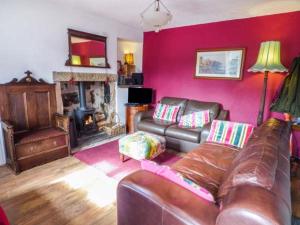 a living room with a leather couch and a fireplace at River Cottage in Bakewell