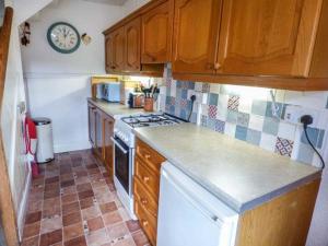 a kitchen with a stove and a clock on the wall at River Cottage in Bakewell
