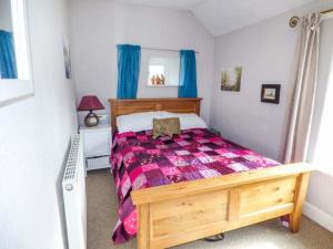 a bedroom with a wooden bed with a purple blanket at River Cottage in Bakewell