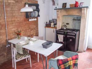 a kitchen with a white table and a stove at Woodland Cottage in Malvern Wells