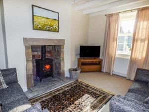 a living room with a fireplace and a tv at Mill Cottage in Wolsingham