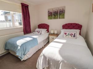 two beds in a small room with a window at Thistleyhaugh Cottage in Morpeth