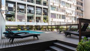 a balcony with a pool and chairs and a building at Duplex charmoso - Ótima localização in Rio de Janeiro