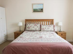 a bedroom with a bed with two nightstands and two lamps at Polpeor in Helston
