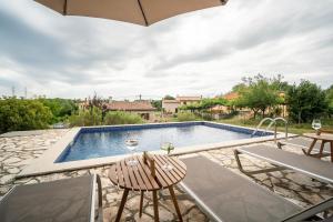 a swimming pool with two chairs and an umbrella at House Luce in Krapan